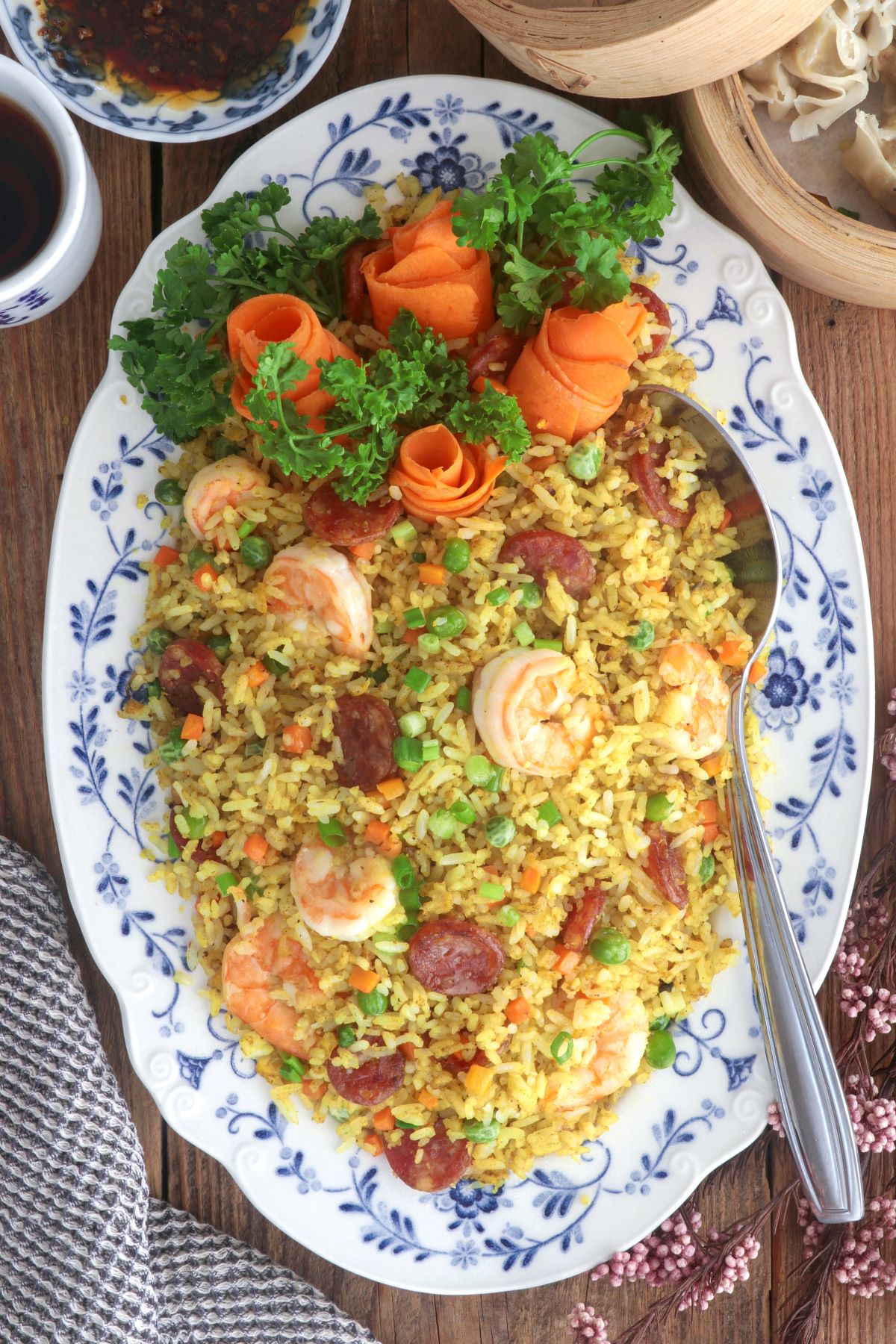 Yang Chow fried rice in a serving platter loaded with shrimp, sausages, eggs, carrots, and green peas.